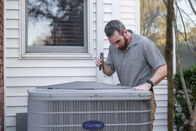 Image of a man looking at an air conditioner on Bookaquote.ca Request a quote for HVAC services in Barrie, Ontario